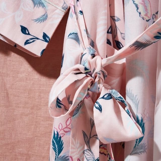 Close detail of a pink bird-print robe tied in a soft bow